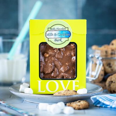 A package of milk and cookies bark with an open window in the packaging to show the brown milk chocolate, studded with marshmallows and cookie crumbles