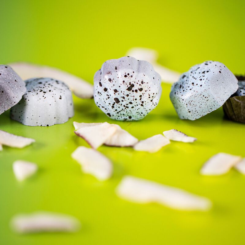 Light blue truffles on lime green background. Coconut shavings in foreground. 