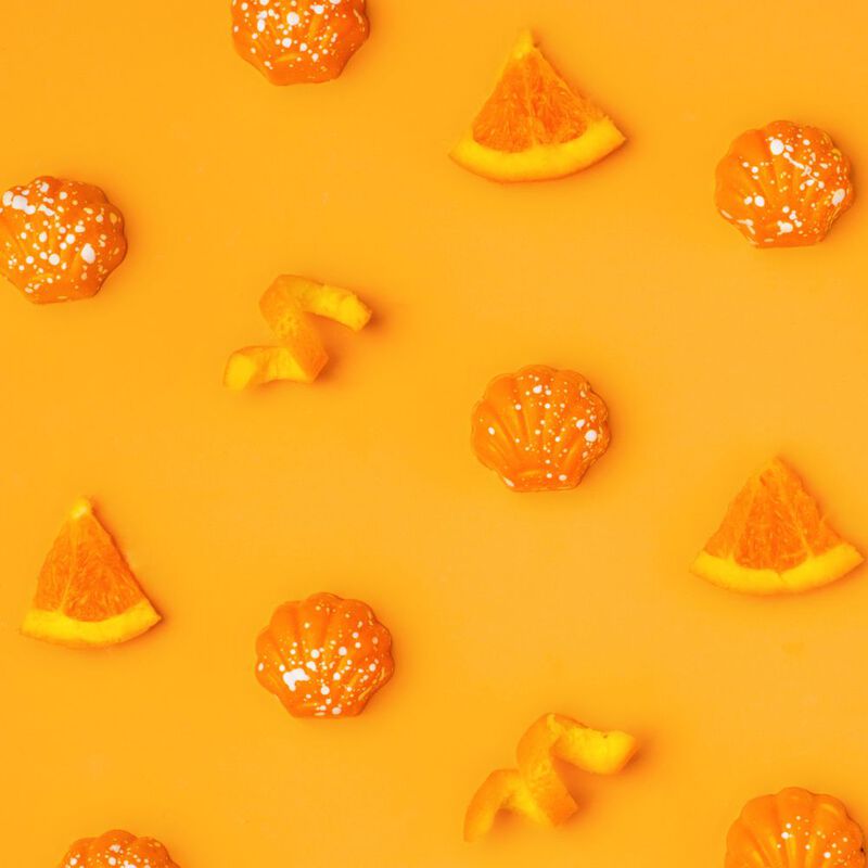 Florida Orange seashell chocolates on an orange background with slices of oranges spread throughout