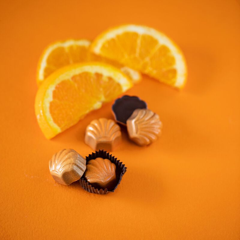 Truffles on orange background. Orange slices featured behind truffles. 