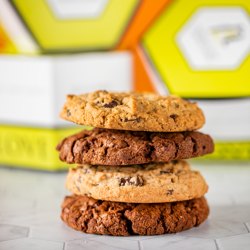 Stack of four cookies with yellow hexagon cookie boxes in background.