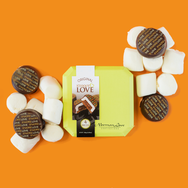 Green S'more Love gift box on orange background. 4 brown circular chocolates on large white marshmallows(left and right of gift box).