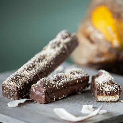 Two chocolate bars with coconut on grey/green background.