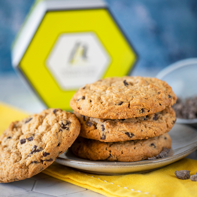 Stack of chocolate chip cookies on blue background. Hexagon yellow cookie box.