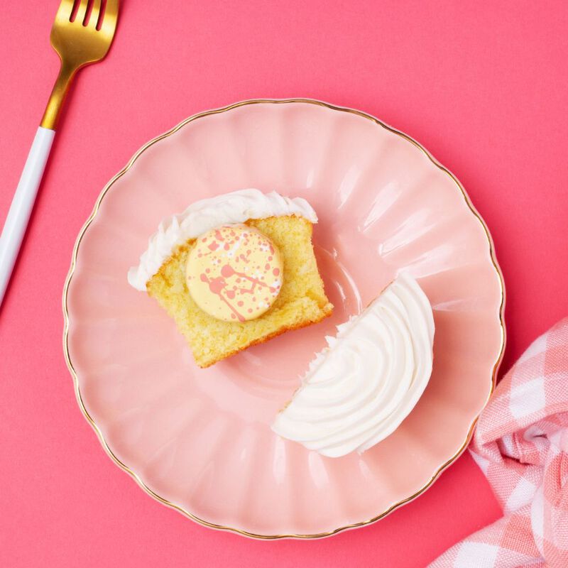 Cupcake Chocolate, on top of a halved vanilla cupcake, sitting on a pink plate with a fork in the periphery