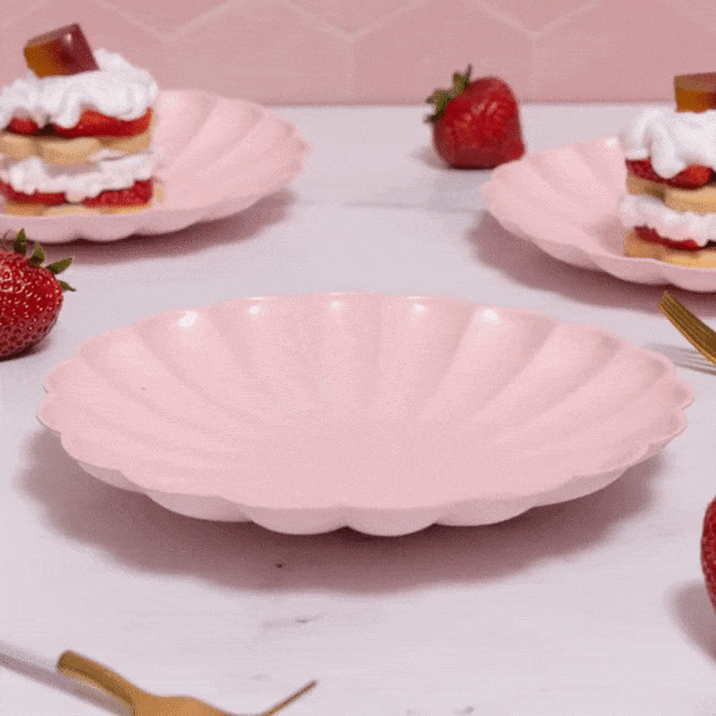 An animated GIF featuring three plates topped with strawberry shortcakes. The middle plate is empty and the cake assembled and disassembled to showcase layers of cake and topped with a red & orange strawberry shortcake chocolate.