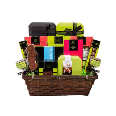 Brown gift basket on white background. Gift basket contains lime green and black boxes of chocolate with black bows; cake pops, chocolate covered almonds, truffles, and a pink wrapped chocolate bar. 
