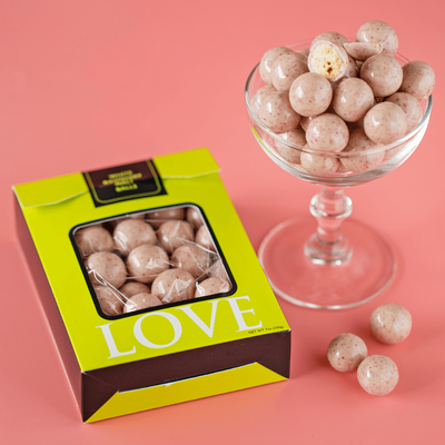 White chocolate raspberry malt balls on peach background.