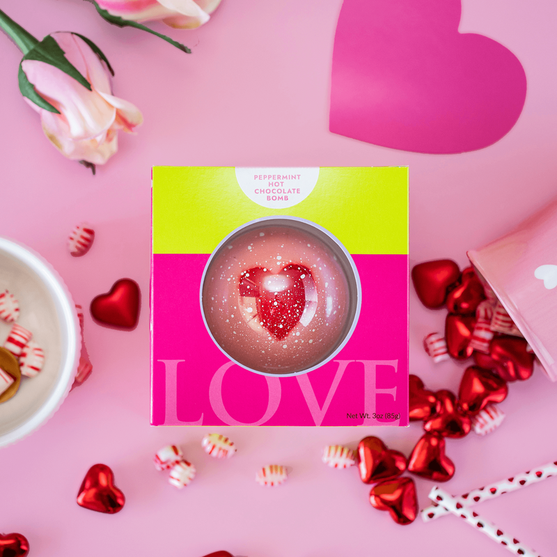 Valentine's Day hot chocolate bomb in pink box on pink background with a pink heart (upper right corner).