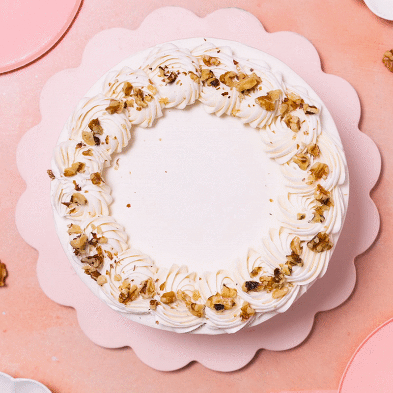 Overhead shot of a cake rimmed with frosting. 8 pieces of blue & green Carrot Cake chocolates appear atop the icing, showing the chocolate's design and shape.