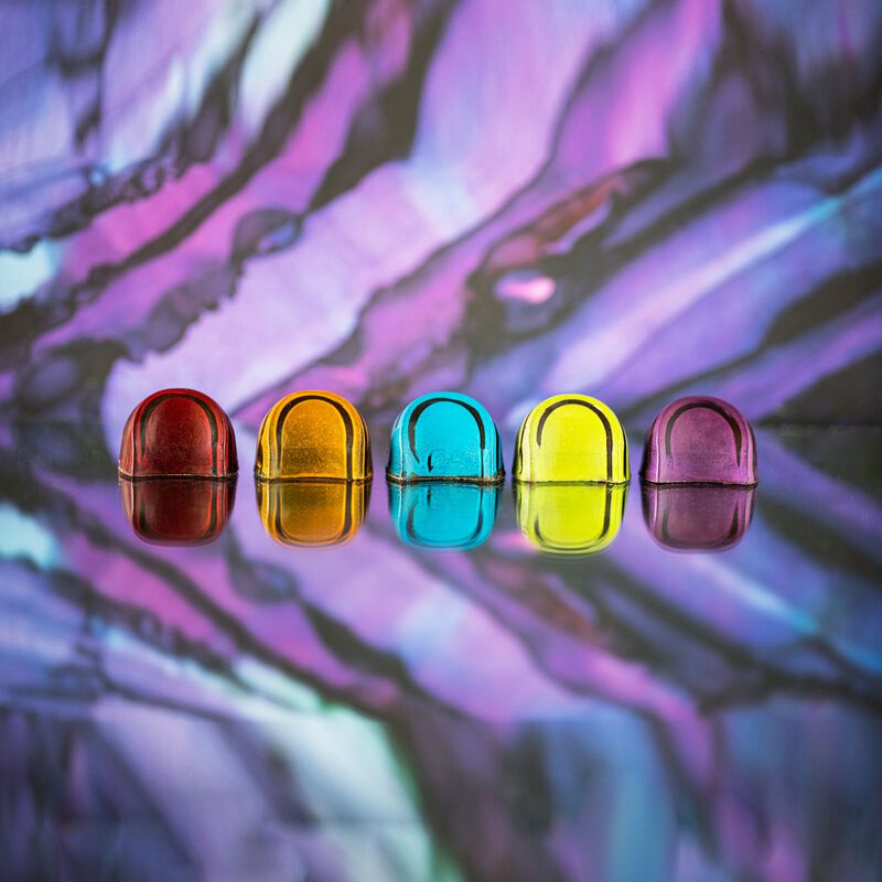 All 5 BLACK dark chocolates in a row, showcasing the different colors and designs of each dark chocolate on a multicolored background. Flavors: Jiquilisco Bay (97%), Maracaibo (88%), Tanzanie (75%), Pico Bonito (70%), Nyangbo (68%).