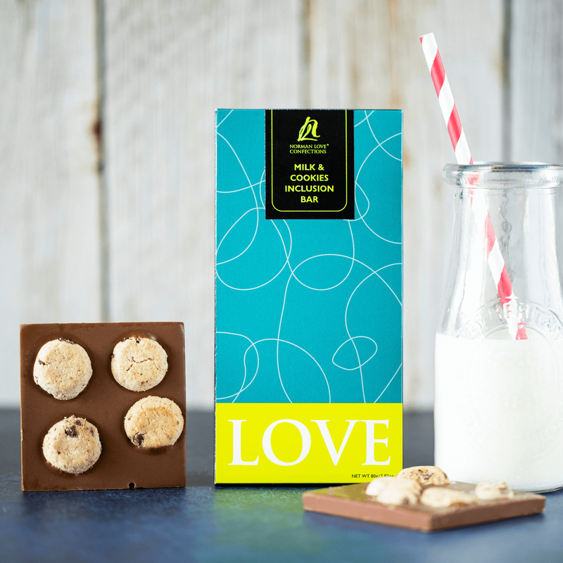 Inclusion bar in teal box with pieces of bar to the side with a glass of milk and straw.