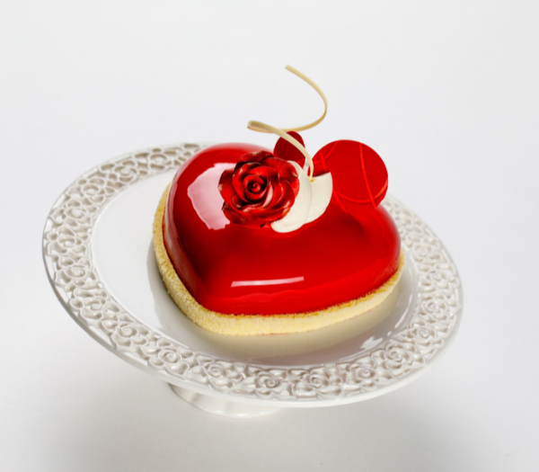 Red dessert with rose decoration on a white display dish.