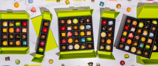 An assortment of open gift boxes featuring various chocolates in different shapes, flavors and colors.